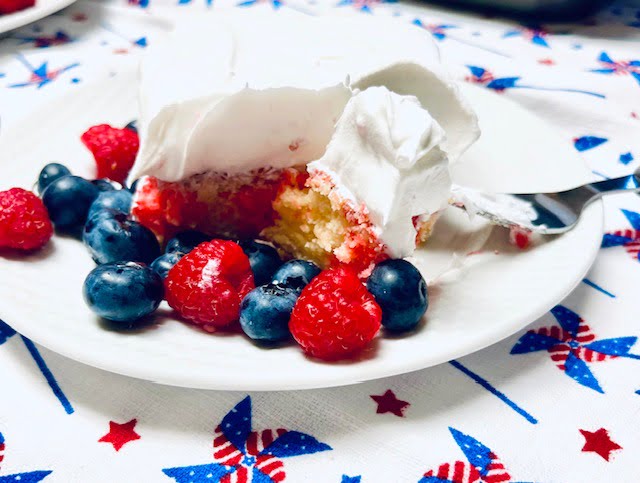 Gluten Free Raspberry poke cake with cool whip frosting and berries 
