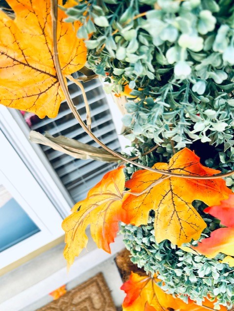 wrapping a fall faux leave vine on the topiary on the porch