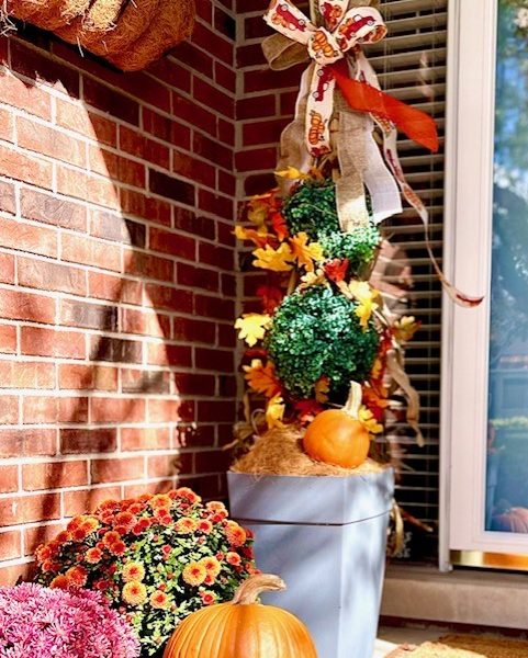 The porch with the pumpkins and mums and the corn stalk with ribbon