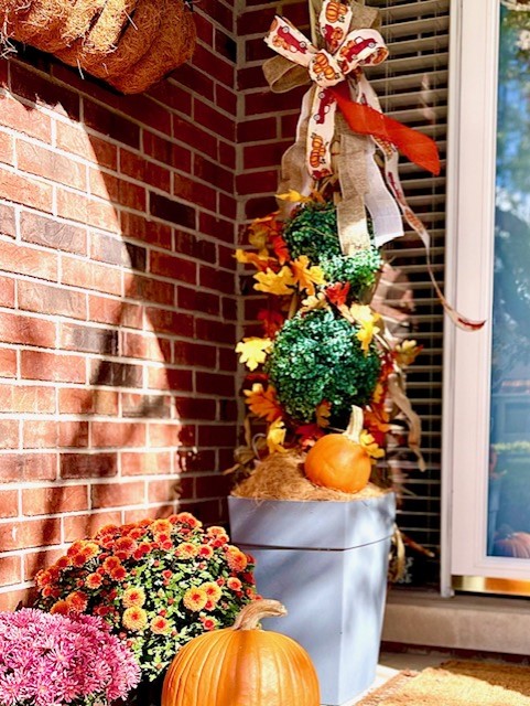 The porch with the pumpkins and mums and the corn stalk with ribbon