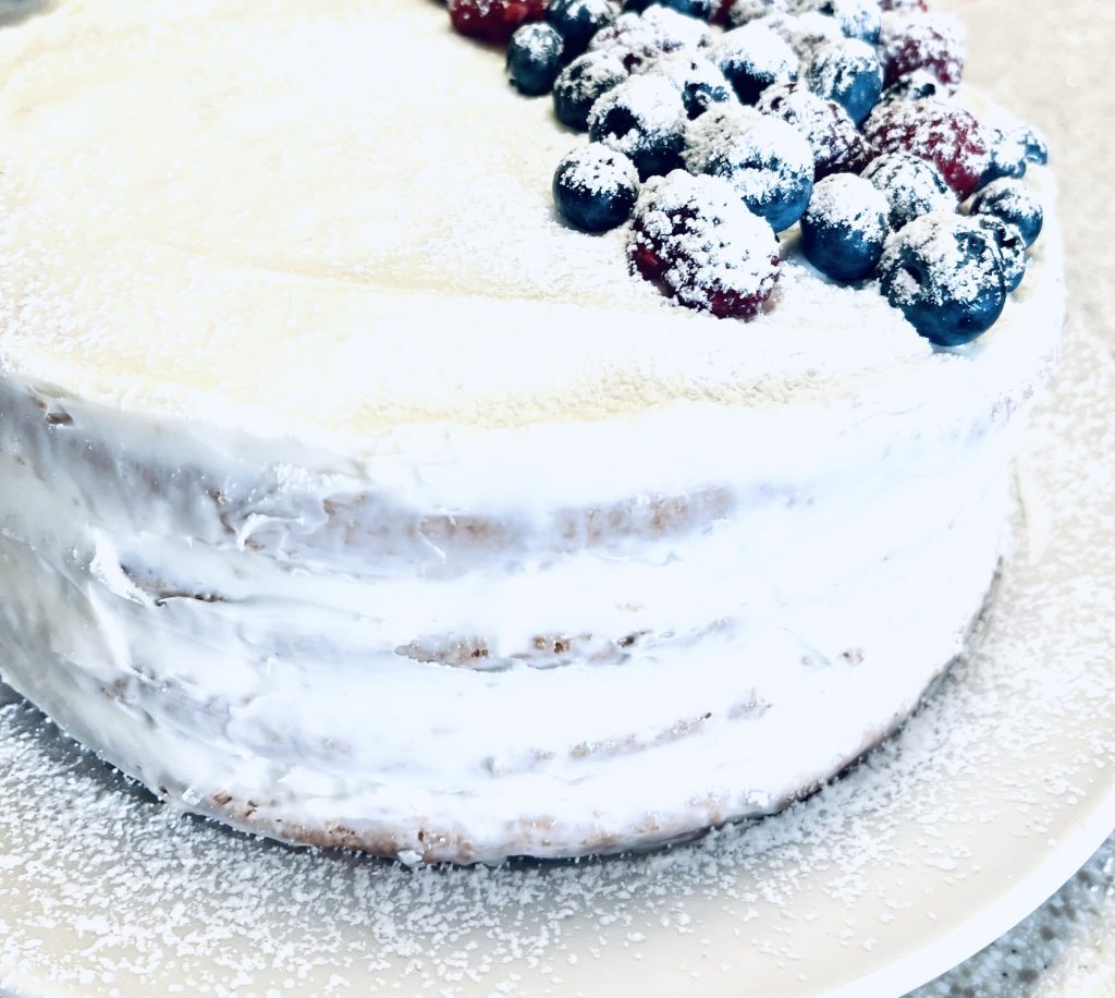 The Most Delicious Very Berry Chantilly Cake Made Gluten Free adding powder sugar to the cake
